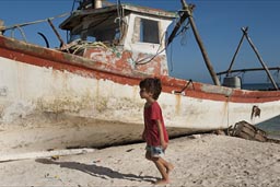 Santa Clara fishing boat, red and white and daniel in red shirt on beach. Yucatan.