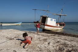 Boys become interested in fishing boats on Santa Clara beach.