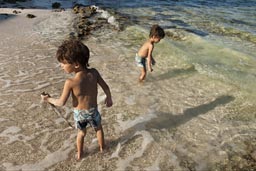 In shallow water in Majuahal, two boys play with a stick.