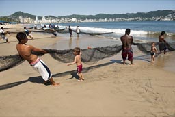 Boys try to help pill the net in, Acapulco, fishing on beach with nets..