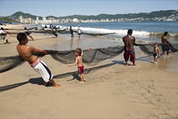Boys try to help pill the net in, Acapulco, fishing on beach with nets..