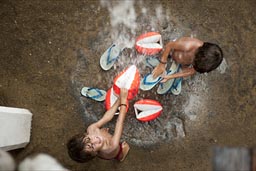 Washing the sand off in rain water, pours from the roof. Zipolite, twin boys.