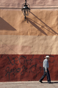 Morelia, a man with hat walks by a colorful house facade.