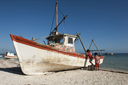 Boys are mounting a fishing boat on santa Clara beach.