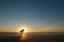 Bech and sunset, surfer and board.