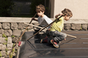 Twin boys play on top of van.