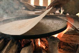 Yuca bread peals of iron plate on wood fire, Amazon basin, Ecuador.