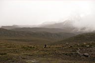 Chimborazo in a misty distance. Men rides a horse in front.