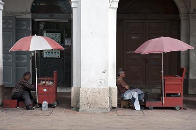 Shoe cleaners wait for clients in Cuenca under arcades. Ecuador.