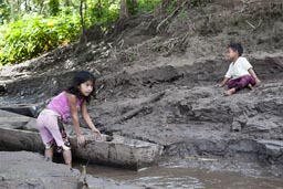 A canoe, muddy banks, the River Huallaga, children play.