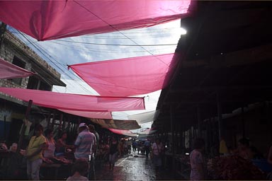 Red tarp against sun, covering market streets in Iquitos, Peru.