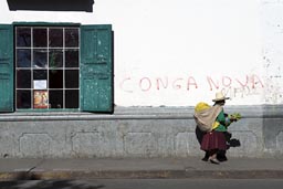 Conga no va! on house in Cajamarca. Indigenas woman with pack and hat walks by.