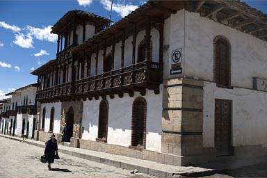 Andean woman walking up white street in Chacas, Peru.,  