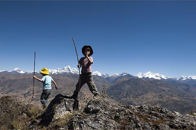 My boys and sticks on top of some rock, in the background, snow capped Cordillera Blanca mountains, Peru.