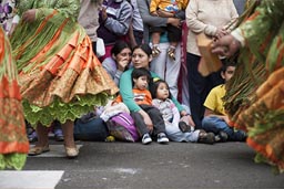 Family and children watch Independence Day parade from the ground. Lima, Peru.