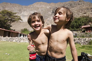 Canyon walls of Colca in back, the boys Daniel and David in Oasis de Sangalle with a Coke bottle, Peru.