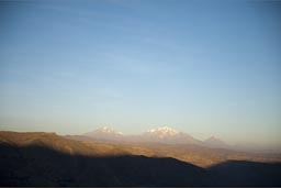 We drive high plateau in Andes and sun sets, in distance Chachani and Misti, volcanoes, Peru.