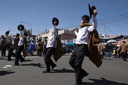Black pants, white shirts, raise hats, men dance down la Avenida de Independencia,  Arequipa Day, Peru.