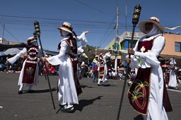 Carrying torches, women veiled like nuns all in white dance on Independence Avenue on Arequipa Day, Peru.